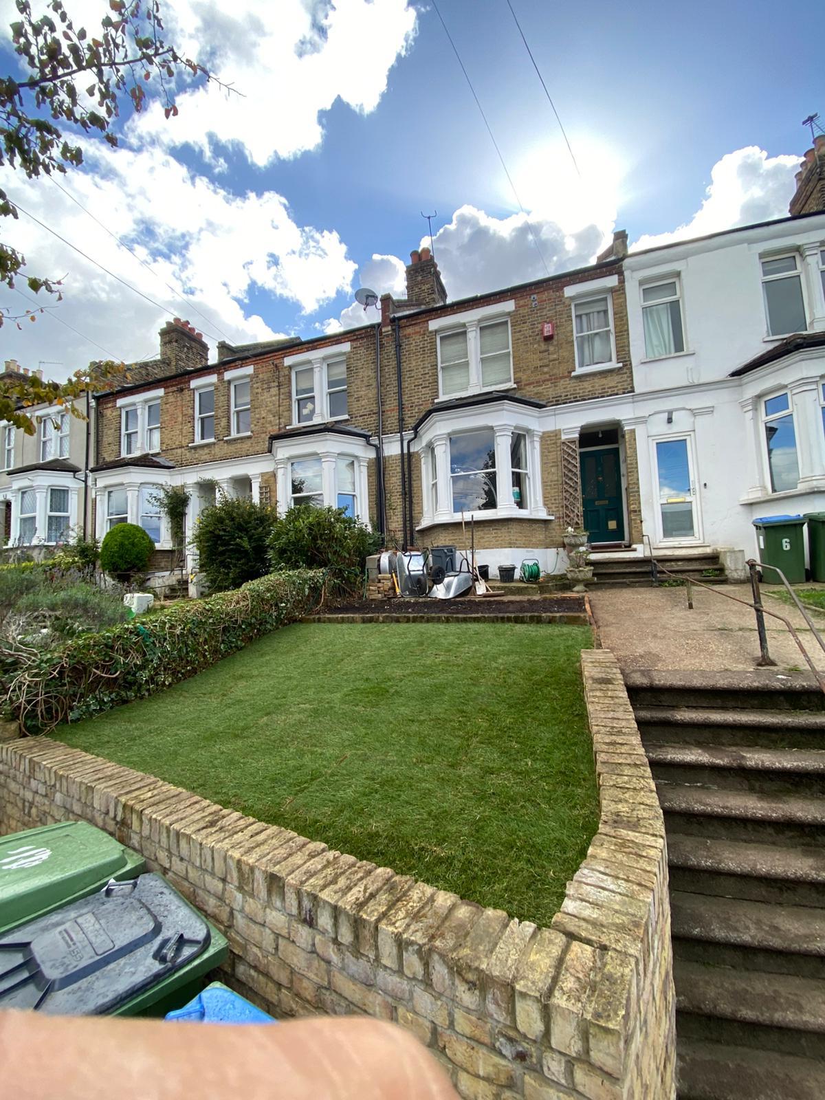 Freshly turfed raised front garden outside a row of London terraces.